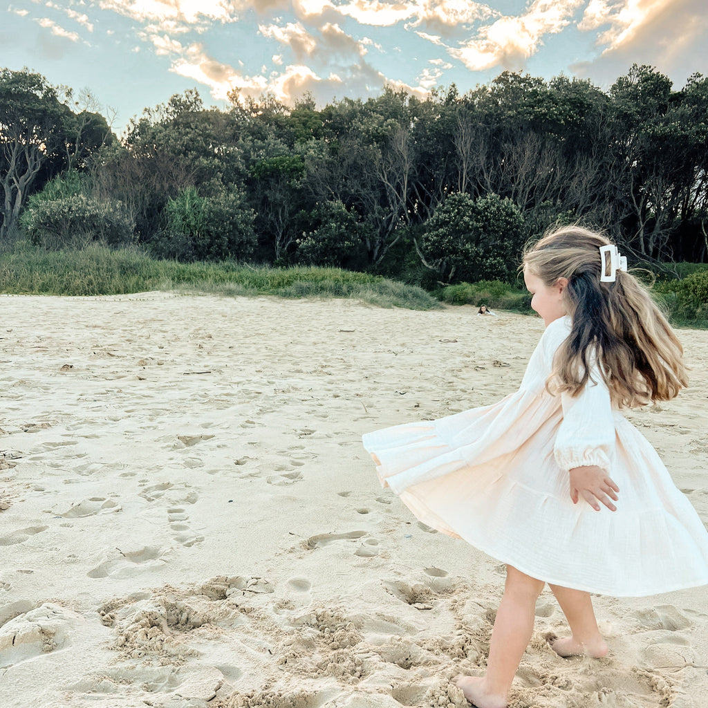 Buttermilk long sleeve smock dress. Handmade from muslin with elastic wrist cuffs and a button closure back. This is the perfect dress for little girls who love to twirl.
