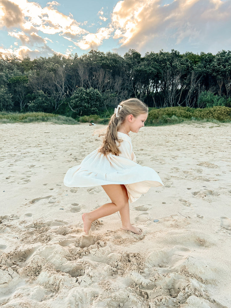 Buttermilk long sleeve smock dress. Handmade from muslin with elastic wrist cuffs and a button closure back. This is the perfect dress for little girls who love to twirl.
