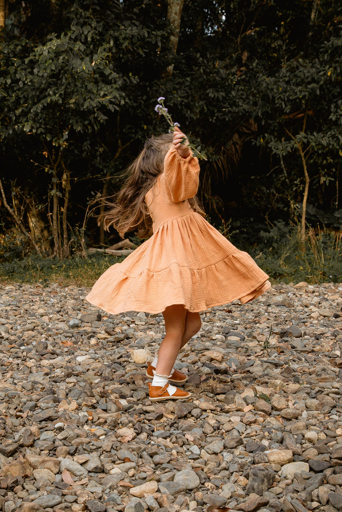 Our smock dress is a stunning piece that is perfect for twirling. Handmade with care in Australia. Made from a soft, lightweight, muted orange papaya muslin fabric, it feels comfortable against your child's skin.
The smock dress features a simple yet elegant design, with a classic round neckline, bell sleeves, and a flowing tiered skirt. The dress is available in a range of sizes to accommodate children of all ages, and its timeless design means it can be worn again and again for years to come.