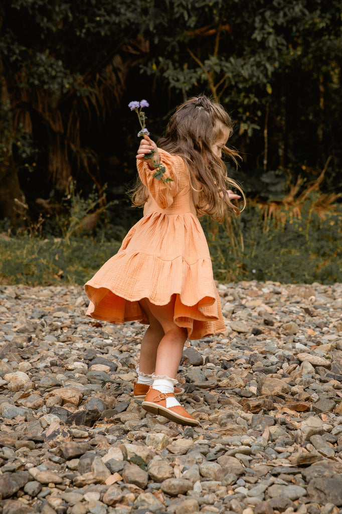 Our smock dress is a stunning piece that is perfect for twirling. Handmade with care in Australia. Made from a soft, lightweight, muted orange papaya muslin fabric, it feels comfortable against your child's skin.
The smock dress features a simple yet elegant design, with a classic round neckline, bell sleeves, and a flowing tiered skirt. The dress is available in a range of sizes to accommodate children of all ages, and its timeless design means it can be worn again and again for years to come.