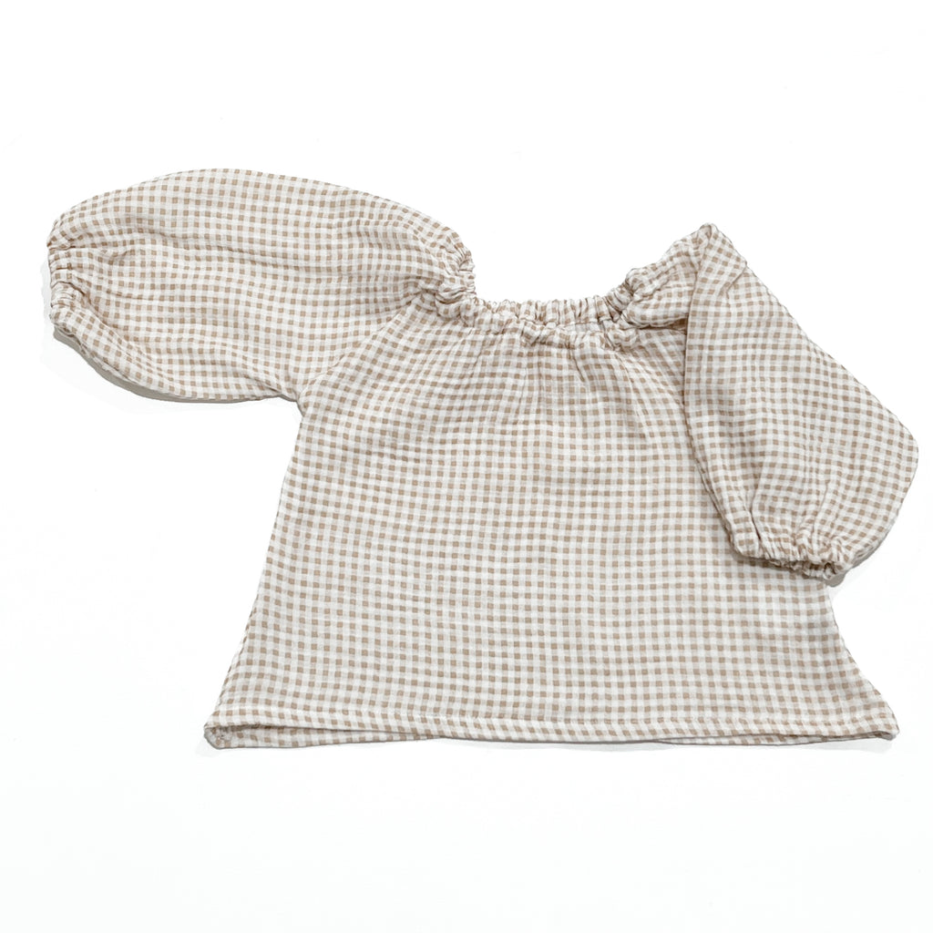 Our handmade smock tops are made with a soft beige oat and white gingham cotton muslin that will just get better with wear age. With a handkerchief hem and elastic cuff bell sleeves, it’s perfect layered under our overalls or paired with our harems, bloomers, frill shorts.
