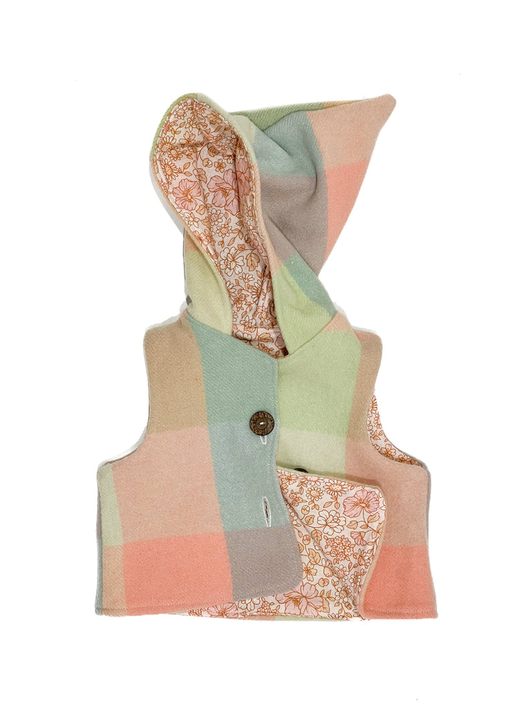 Handmade vests are made from 100% wool ~ upcycled from a blanket in excellent condition. This vest is fully lined with our coral flora linen / cotton fabric. 

Absolutely gorgeous on and perfect for layering, with a hood to keep their ears warm.

The vests are true to size. You can size up to get 2 winter seasons out of them. 
