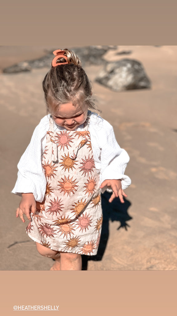 Our handmade smock tops are made with a soft white cotton muslin that will just get better with wear age. With a handkerchief hem and elastic cuff bell sleeves, it’s perfect layered under our overalls or paired with our harems, bloomers, frill shorts.